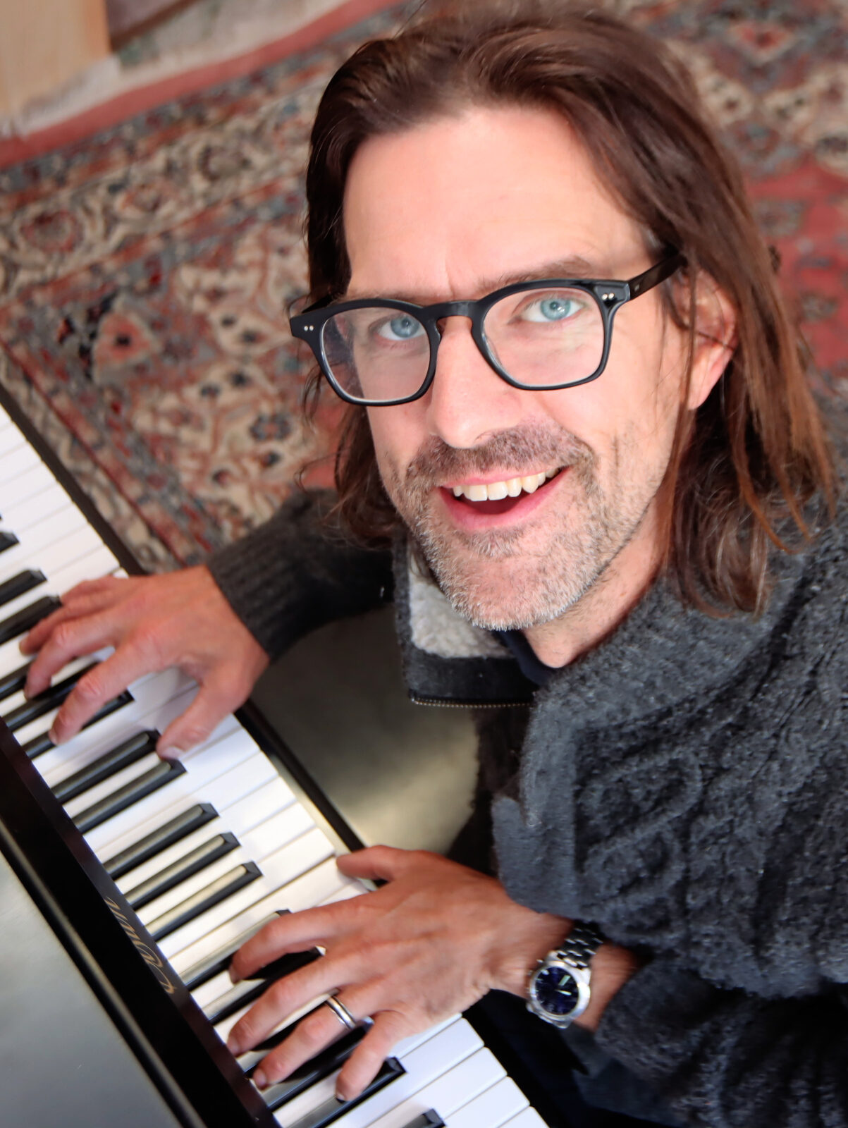 Image of Dan Corbett smiling and playing the piano.